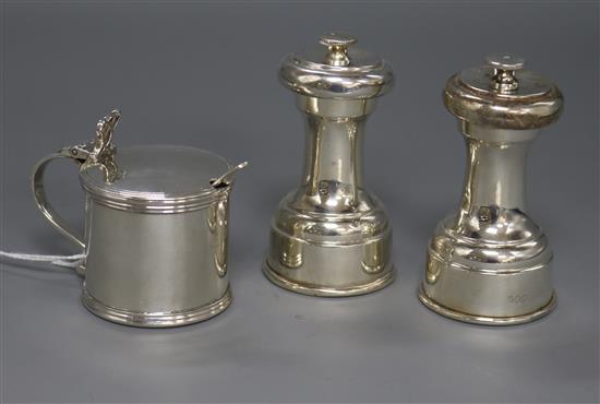 A pair of George V silver pepper grinders by Hukin & Heath and a silver mustard pot.